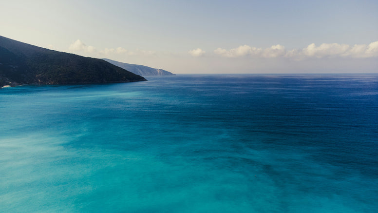 Clear blue water with a mountainous coastline on a clear day